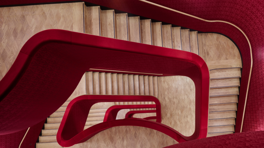 Treppenabgang mit rotem Geländer und hölzernen Stufen