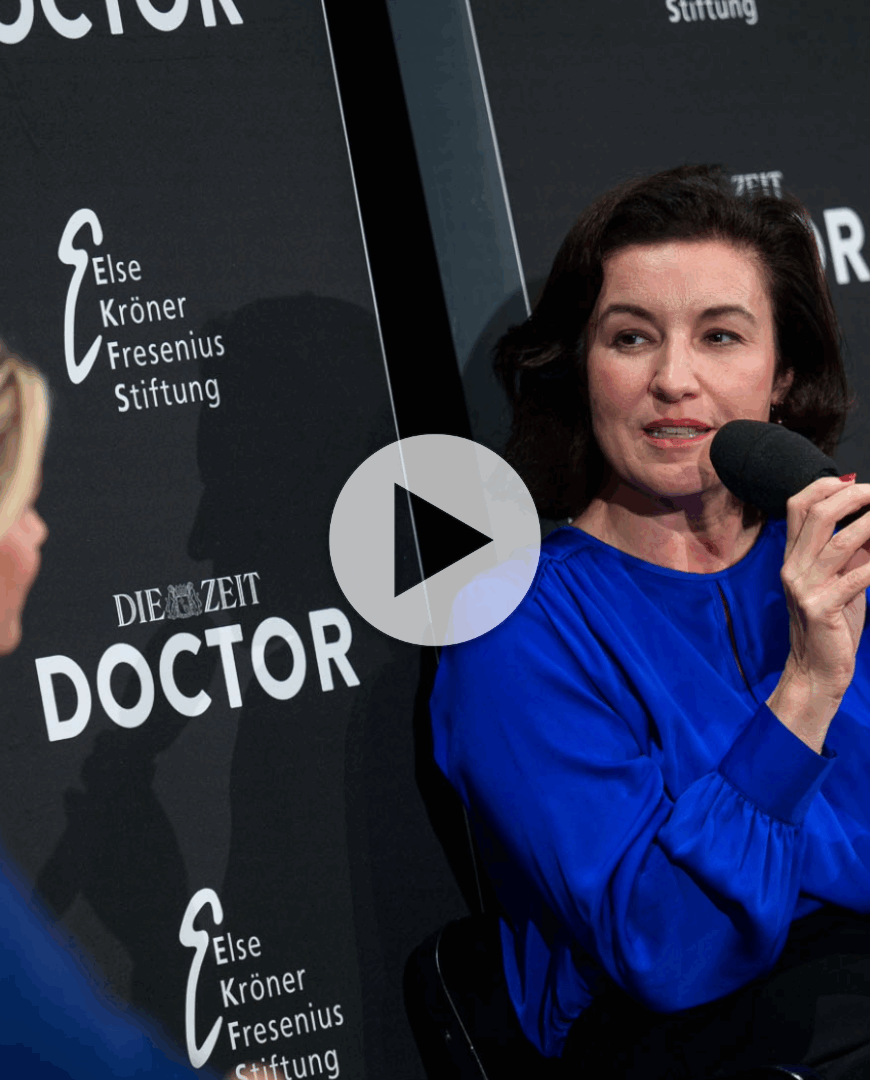 Dorothee Bär im Gespräch. Sie trägt blau und sitzt vor einem schwarzen Hintergrund.