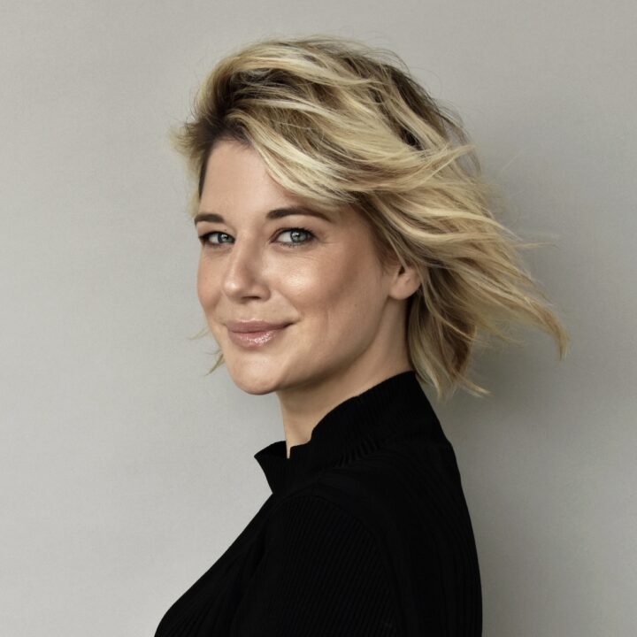 Frau mit blonden Haaren, schwarzes Oberteil.
